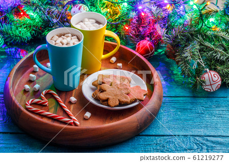 Photo of New Year's cookies, cookies, two mugs with cocoa with marshmallow, caramel sticks, branches of spruce 61219277