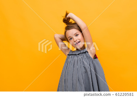 cute charming girl child in a dress holds hair with hands on a yellow background with copy space cute charming girl child in a dress holds hair with hands on a yellow background with copy space 61220581