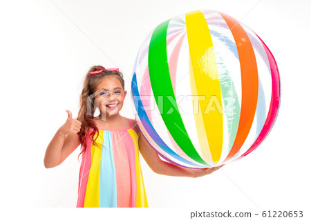 happy girl holding a striped bright inflatable swimming ball and shows a class on a white background 61220653