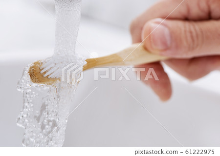 man using a bamboo toothbrush in the bathroom 61222975