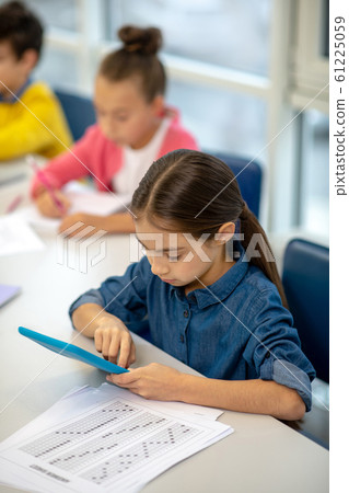 Girl working in the class using her tablet Girl working in the class using her tablet 61225059