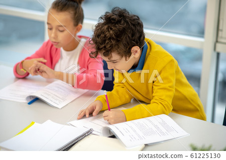 Schoolboy meticulously working on his assignment in class Schoolboy meticulously working on his assignment in class 61225130