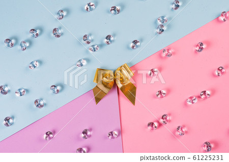 Golden ribbon ending with crystals in blue pink background, top view. 61225231