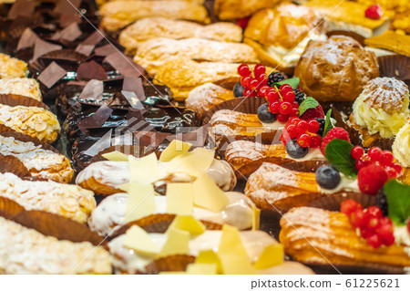 Pastry shop with variety of donuts, muffins, creme brulee, cakes with fruits and berries 61225621