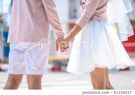 Cropped image of new marriage holding hands across the road 61226017