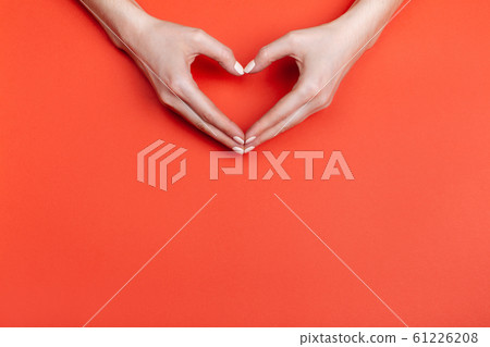 Female hands show a heart symbol on a red background. Place for text Female hands show a heart symbol on a red background. Place for text 61226208