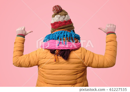 Young man in winter hats and scarfs pointing with fingers on himself. 61227535