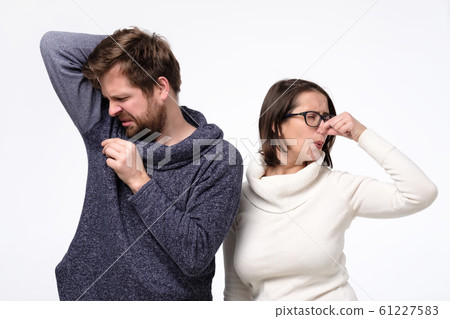 Young man with sweat stain on his clothes and caucasian woman feeling bad smell. 61227583