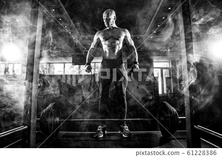 Bodybuilder preparing for deadlift of barbell. Smoke 61228386