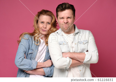 Mature couple frowning with their arms crossed listening to bad news. 61228831