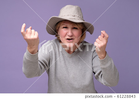 Mature woman in summer hat standing and looking at camera and screaming. Mature woman in summer hat standing and looking at camera and screaming. 61228843