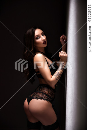 Portrait of a young glamorous lady in black linegrie posing near wall Portrait of a young glamorous lady in black linegrie posing near wall 61228911