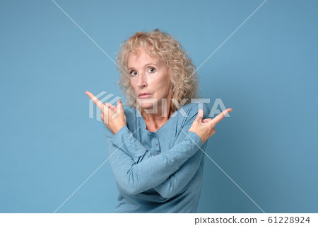 Mature blonde woman pointing to both sides with fingers in different direction 61228924