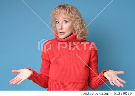 Woman throws up hands shrugging her shoulders being unsure having some doubts 61229059