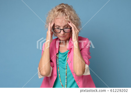 Mature caucasian woman in colored clothes touching her thead feeling stress Mature caucasian woman in colored clothes touching her thead feeling stress 61229202