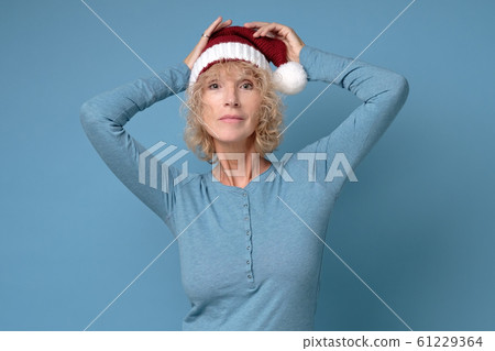 Pretty christmas woman in red santa hat, smiling isolated on blue background Pretty christmas woman in red santa hat, smiling isolated on blue background 61229364