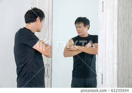 一個人在鏡子前檢查他的身體 61235054