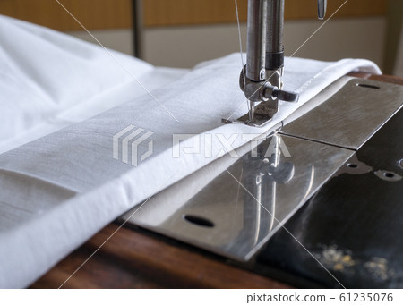 Node of antique manual sewing machine with piece of white fabric. Presser foot, needle bar, throat plate, close up, selected focus. 61235076