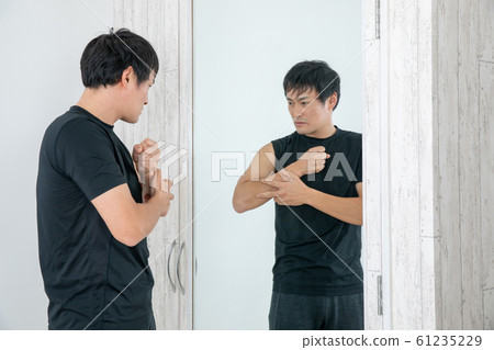 A man checking his body in front of a mirror 61235229