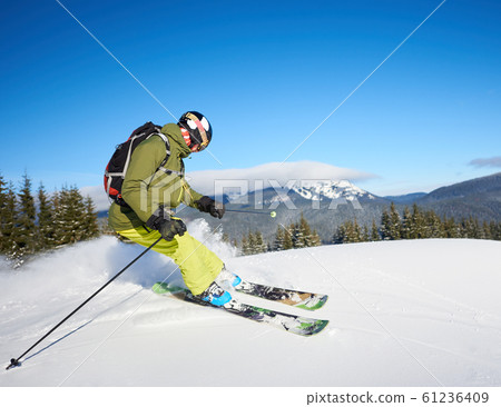 Young man backpacker skiing up and down slopes. Male skier training in sunny winter day. Backcountry skiing concept. 61236409