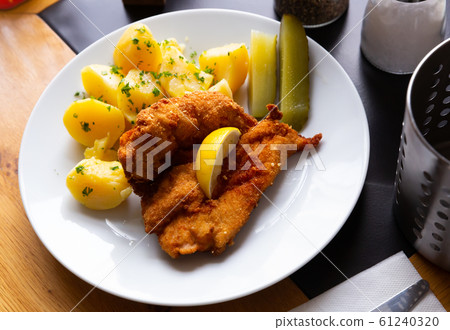 Chicken fillet in batter with Parmesan with potatoes and pickled cucumbers Chicken fillet in batter with Parmesan with potatoes and pickled cucumbers 61240320