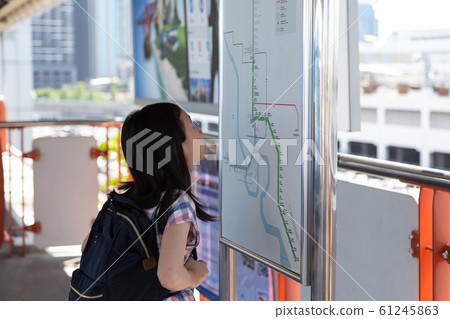 Asian girl orientating herself on the public transport map,Student looks at maps with public transport for travel in the big city,Search transport links on map urban transport 61245863