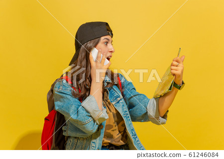 Portrait of a cheerful young caucasian tourist girl isolated on yellow background 61246084