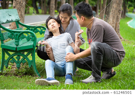 Sick little child girl with epileptic seizures in outdoor park,daughter suffering from seizures,illness with epilepsy during seizure attack,asian mother,father care of girl patient,brain,nervous syste 61246501