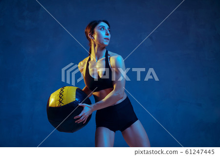 Caucasian young female athlete practicing on blue studio background in neon light 61247445