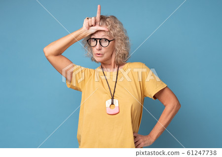 Annoyed woman, showing loser sign standing with disrespectful expression Annoyed woman, showing loser sign standing with disrespectful expression 61247738