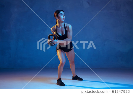 Caucasian young female athlete practicing on blue studio background in neon light 61247933