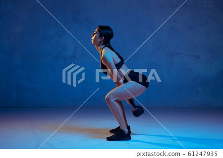 Caucasian young female athlete practicing on blue studio background in neon light 61247935