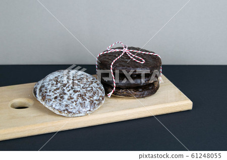 Chocolate ginger biscuits laid out on a wooden board, which stands on a black table Chocolate ginger biscuits laid out on a wooden board, which stands on a black table 61248055