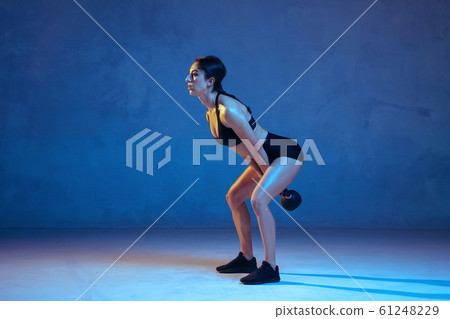 Caucasian young female athlete practicing on blue studio background in neon light 61248229