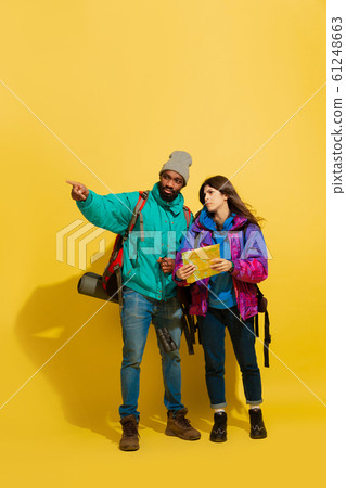 Portrait of a cheerful young tourist couple isolated on yellow background Portrait of a cheerful young tourist couple isolated on yellow background 61248663