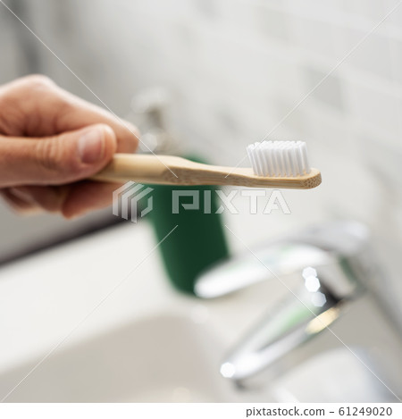 man using a bamboo toothbrush in the bathroom 61249020