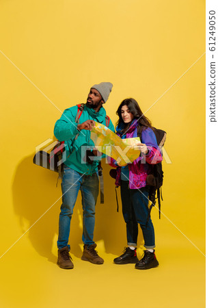 Portrait of a cheerful young tourist couple isolated on yellow background 61249050
