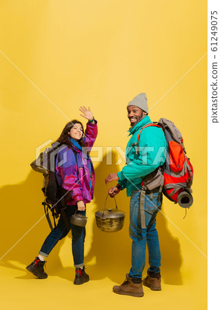 Portrait of a cheerful young tourist couple isolated on yellow background 61249075