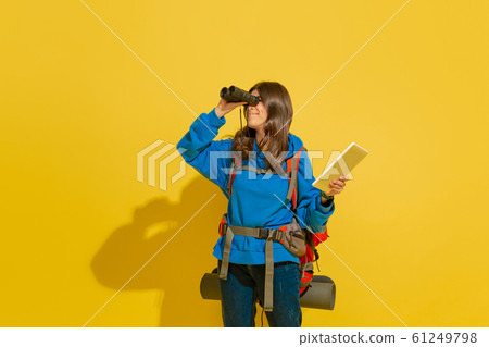 Full length portrait of a cheerful young caucasian tourist girl isolated on yellow background Full length portrait of a cheerful young caucasian tourist girl isolated on yellow background 61249798