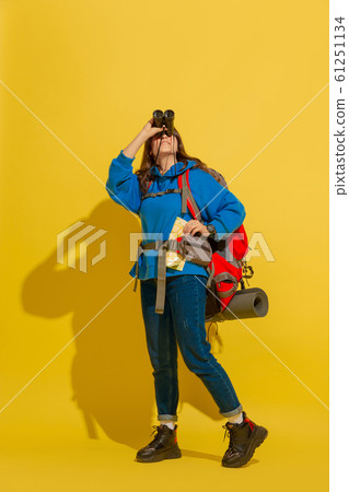 Full length portrait of a cheerful young caucasian tourist girl isolated on yellow background Full length portrait of a cheerful young caucasian tourist girl isolated on yellow background 61251134