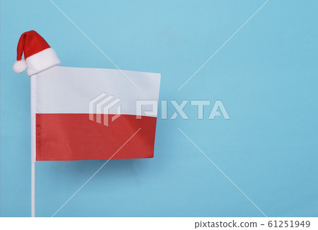 Flag of Poland with little santa claus hat on blue background. New Year winter holiday concept, copy space Flag of Poland with little santa claus hat on blue background. New Year winter holiday concept, copy space 61251949