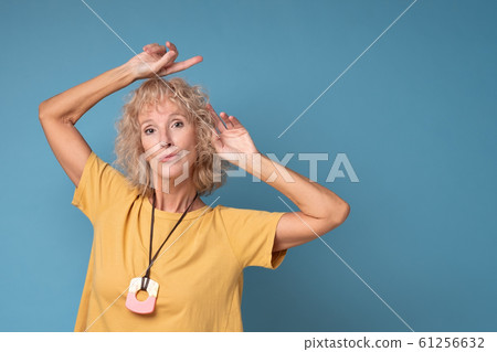 Mature blonde cheerful woman looking aside pointing. 61256632