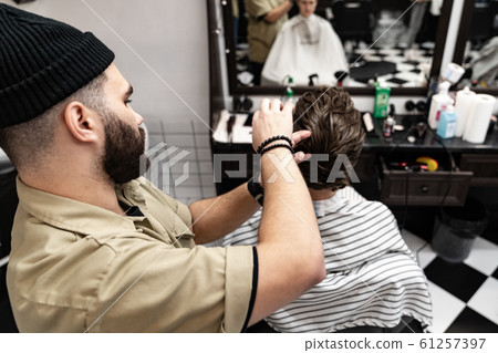 Men's haircut. Stylish hairdresser cuts a man. 61257397