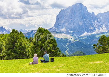 Two elderly people seen at Seceda peak in the background view of the mountain Sassolungo or Longkofel Traveling to village St. Cristina di Val Gardena, Bolzano, Italy, Dolomites, Trentino alto, Italy 61258005