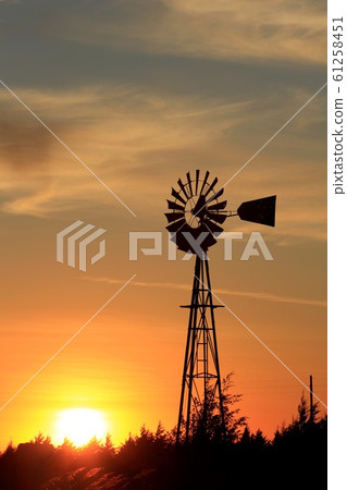 Kansas colorful Sunset with clouds,tree's, and a Windmill Silhouette west of Nickerson Kansas USA out in the country. Kansas colorful Sunset with clouds,tree's, and a Windmill Silhouette west of Nickerson Kansas USA out in the country. 61258451