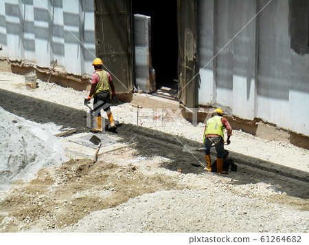 Construction workers creating concrete road curb at the construction site. They are using the in-situ method using the standard metal mold. Construction workers creating concrete road curb at the construction site. They are using the in-situ method using the standard metal mold. 61264682