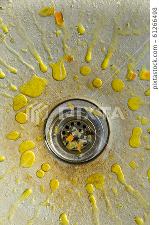 A dirty and littered sink with yellow grease stains. 61266498