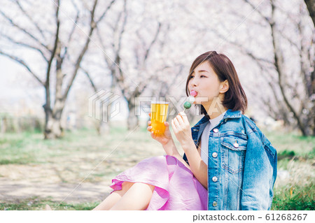 Woman eating cherry blossom viewing dumpling 61268267