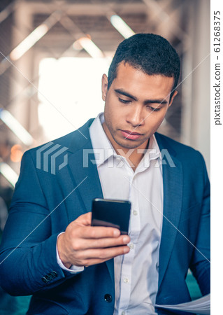 Dark-haired young man in jacket looking attentive 61268375