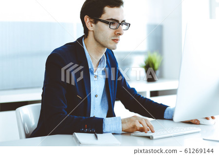 Businessman working with computer in modern office. Headshot of male entrepreneur or company manager at workplace. Business concept Businessman working with computer in modern office. Headshot of male entrepreneur or company manager at workplace. Business concept 61269144